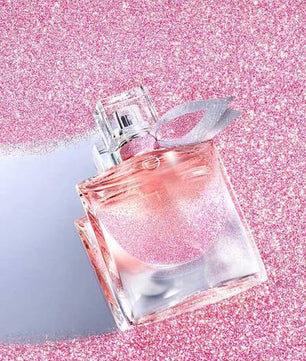 Pink perfume bottle with silver cap on a pink glittery background