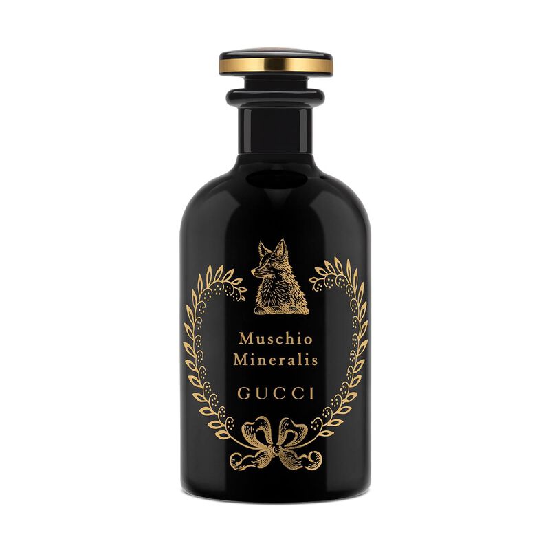 Black Gucci perfume bottle with gold accents on a white background