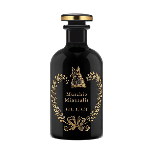 Black Gucci perfume bottle with gold accents on a white background