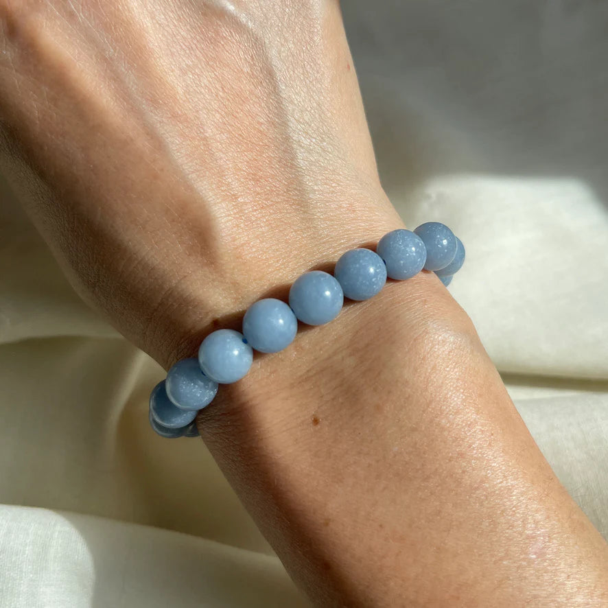Blue beaded bracelet on a wrist with a neutral background