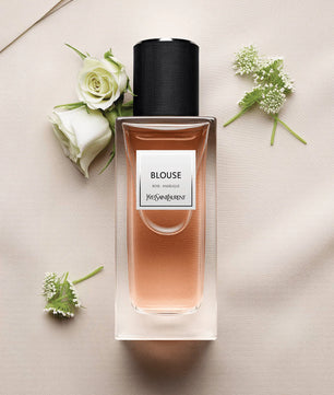 Perfume bottle labeled 'Blouse' by Yves Rocher on a light surface with flowers.
