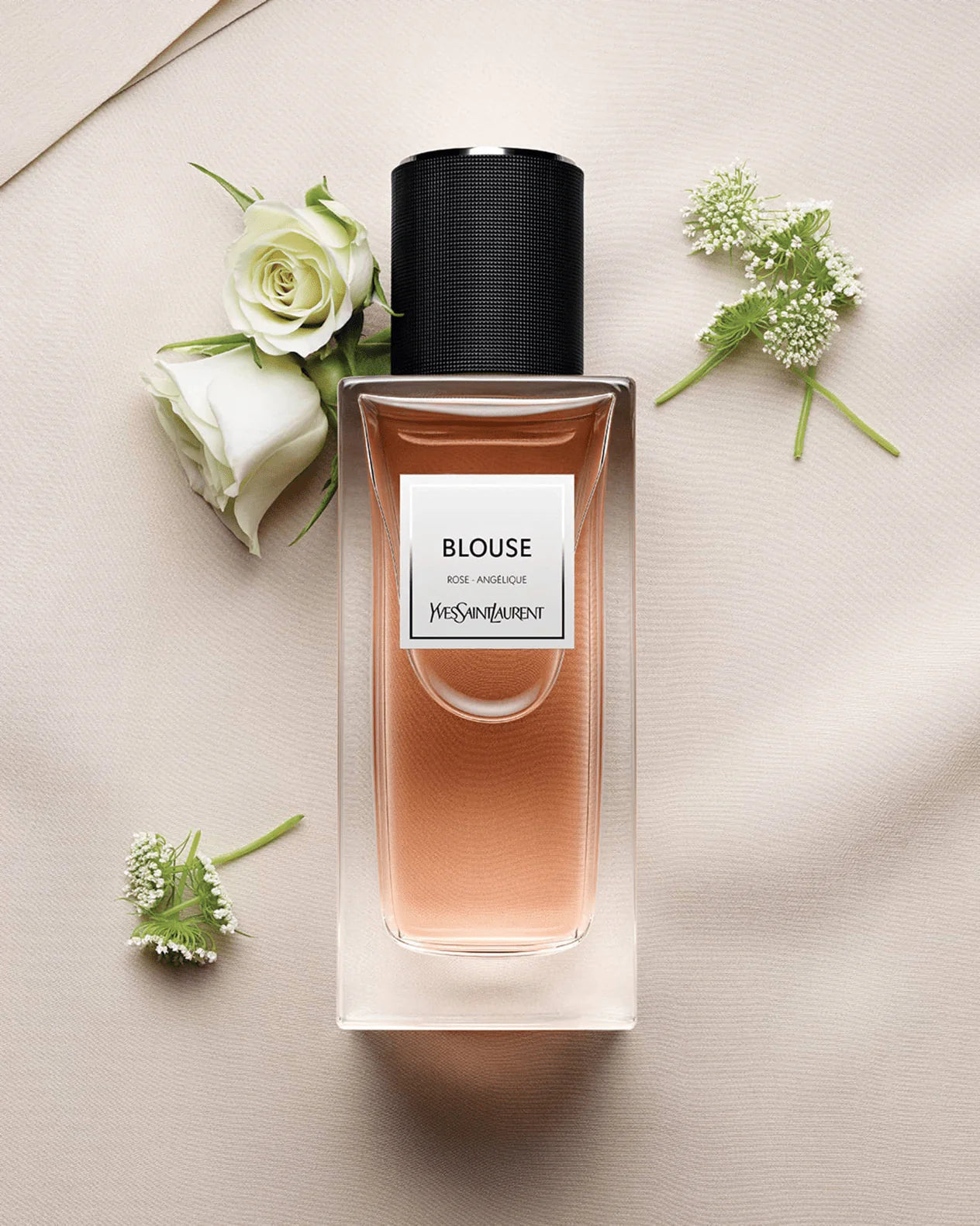 Perfume bottle labeled 'Blouse' by Yves Rocher on a light surface with flowers.