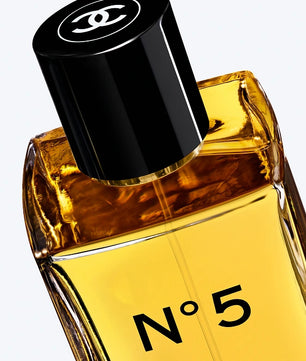 Chanel No. 5 Eau de Parfum bottle with amber-colored liquid, a black cap featuring the iconic interlocking CC logo, and 'N°5' printed on the front, set against a clean white background.