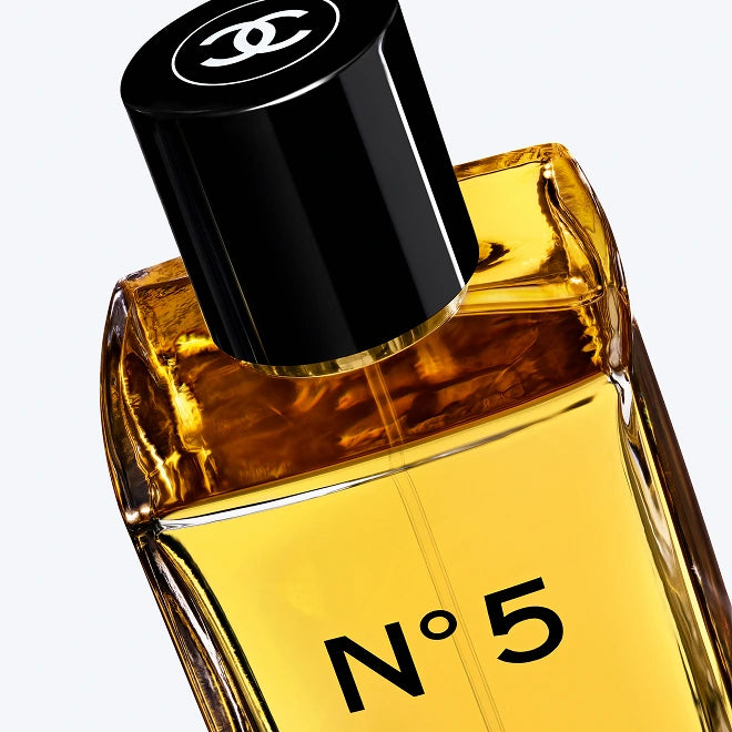 Chanel No. 5 Eau de Parfum bottle with amber-colored liquid, a black cap featuring the iconic interlocking CC logo, and 'N°5' printed on the front, set against a clean white background.
