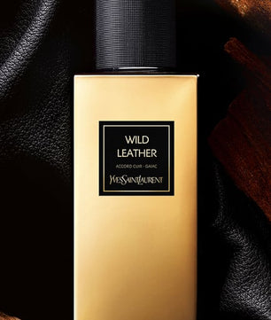 Gold bottle of Yves Saint Laurent Wild Leather perfume on a dark textured background
