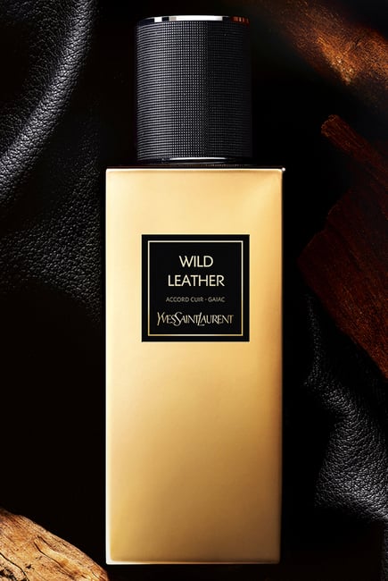 Gold bottle of Yves Saint Laurent Wild Leather perfume on a dark textured background