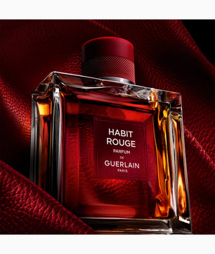 Bottle of Guerlain Habit Rouge perfume on a red background