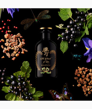 Gucci perfume bottle surrounded by flowers and leaves on a dark background