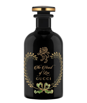 Black Gucci perfume bottle with gold and green design on a white background