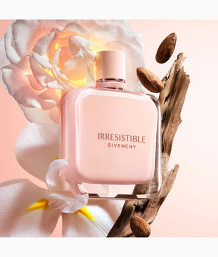 Givenchy Irresistible perfume bottle with flowers and wood elements on a soft pink background