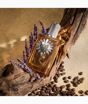 Perfume bottle with decorative cap on a rustic background with lavender and coffee beans