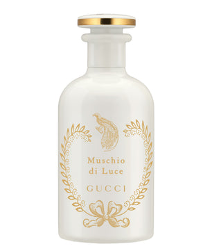 Gucci Muschio di Luce perfume bottle in frosted white glass with gold foil detailing and a gold cap, set against a plain white background.