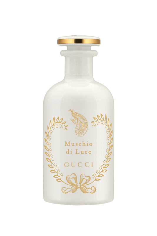 Gucci Muschio di Luce perfume bottle in frosted white glass with gold foil detailing and a gold cap, set against a plain white background.