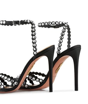 Black high-heeled sandals with beaded straps on a white background