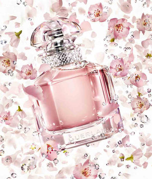 Pink Guerlain perfume bottle on a floral background