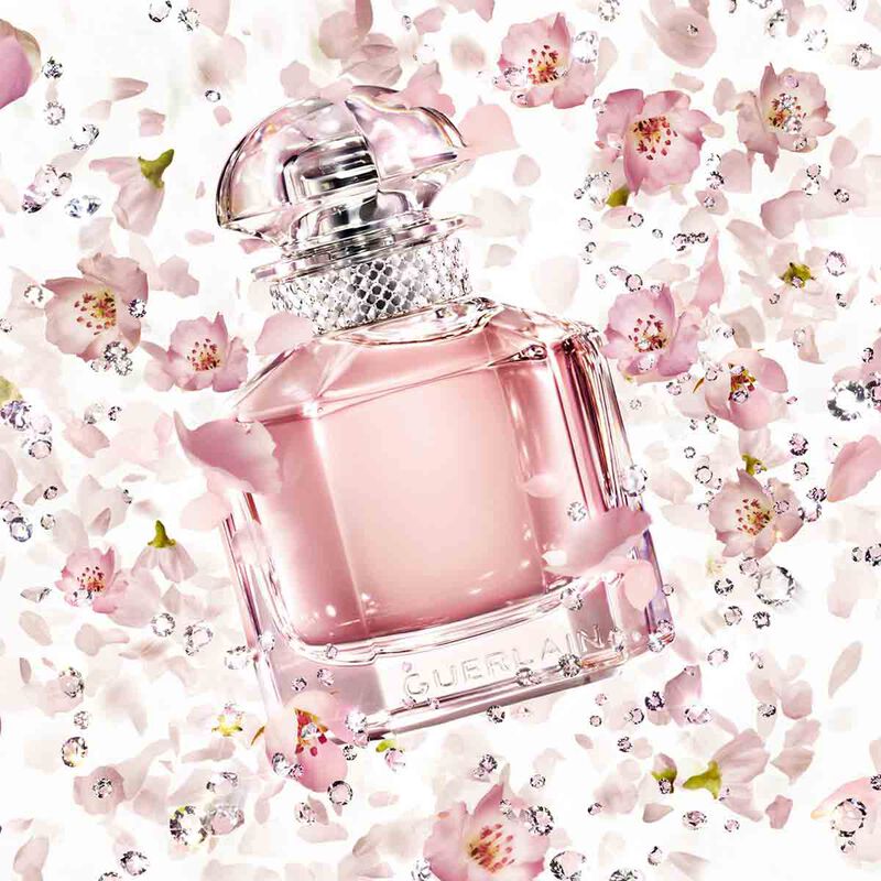 Pink Guerlain perfume bottle on a floral background