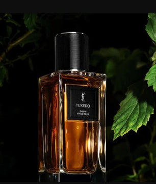 Perfume bottle labeled 'Tuxedo' with a dark background and green leaves.