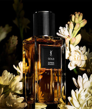 YSL Gold perfume bottle with flowers on a dark background