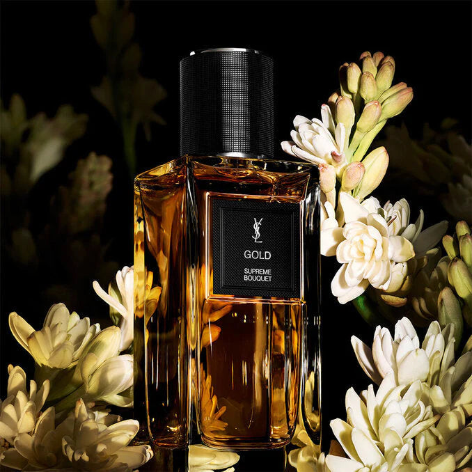 YSL Gold perfume bottle with flowers on a dark background