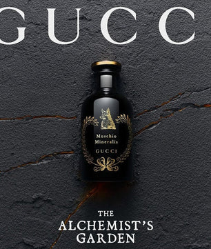 Gucci bottle with 'The Alchemist's Garden' text on a dark textured background