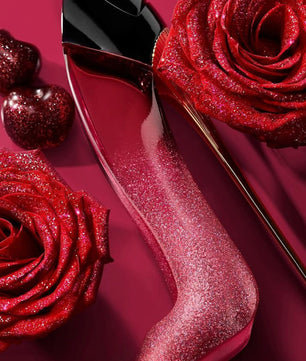 Red glittery nail polish bottle with a rose on a red background