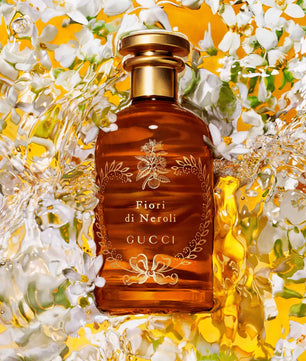 Gucci Fiori di Neroli perfume bottle surrounded by flowers on a yellow background