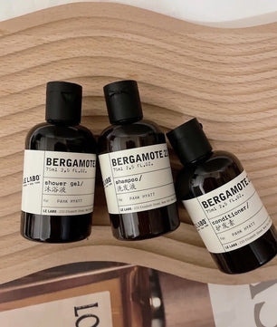 Three bottles of Bergamote products by Le Labo on a wooden surface.