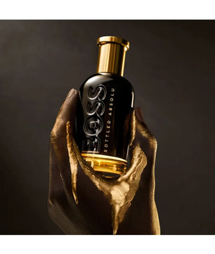 Bottle of Hugo Boss perfume held by a hand against a dark background