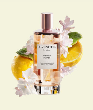 Perfume bottle labeled 'Lovenotes by ariana' with lemons and flowers on a light yellow background