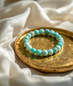 Turquoise beaded bracelet on a gold plate with white fabric background