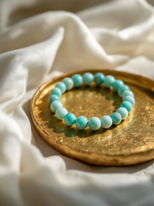Turquoise beaded bracelet on a gold plate with white fabric background