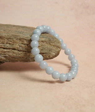 Light blue beaded bracelet on a stone with a soft pink background