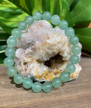 Green beaded bracelet on a crystal formation with green leaves in the background