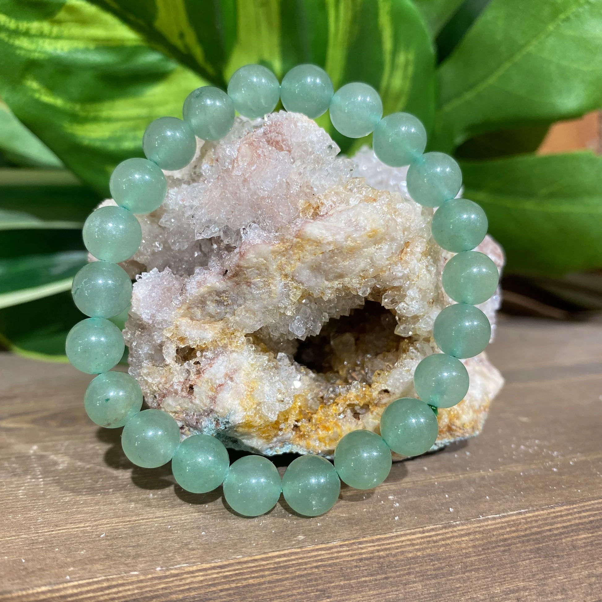Green beaded bracelet on a crystal formation with green leaves in the background