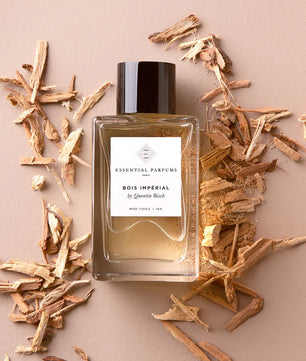 Perfume bottle labeled 'Bois Imperial' by Essential Parfums on a beige background with wood chips.