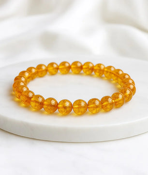 Yellow beaded bracelet on a white plate with a white fabric background