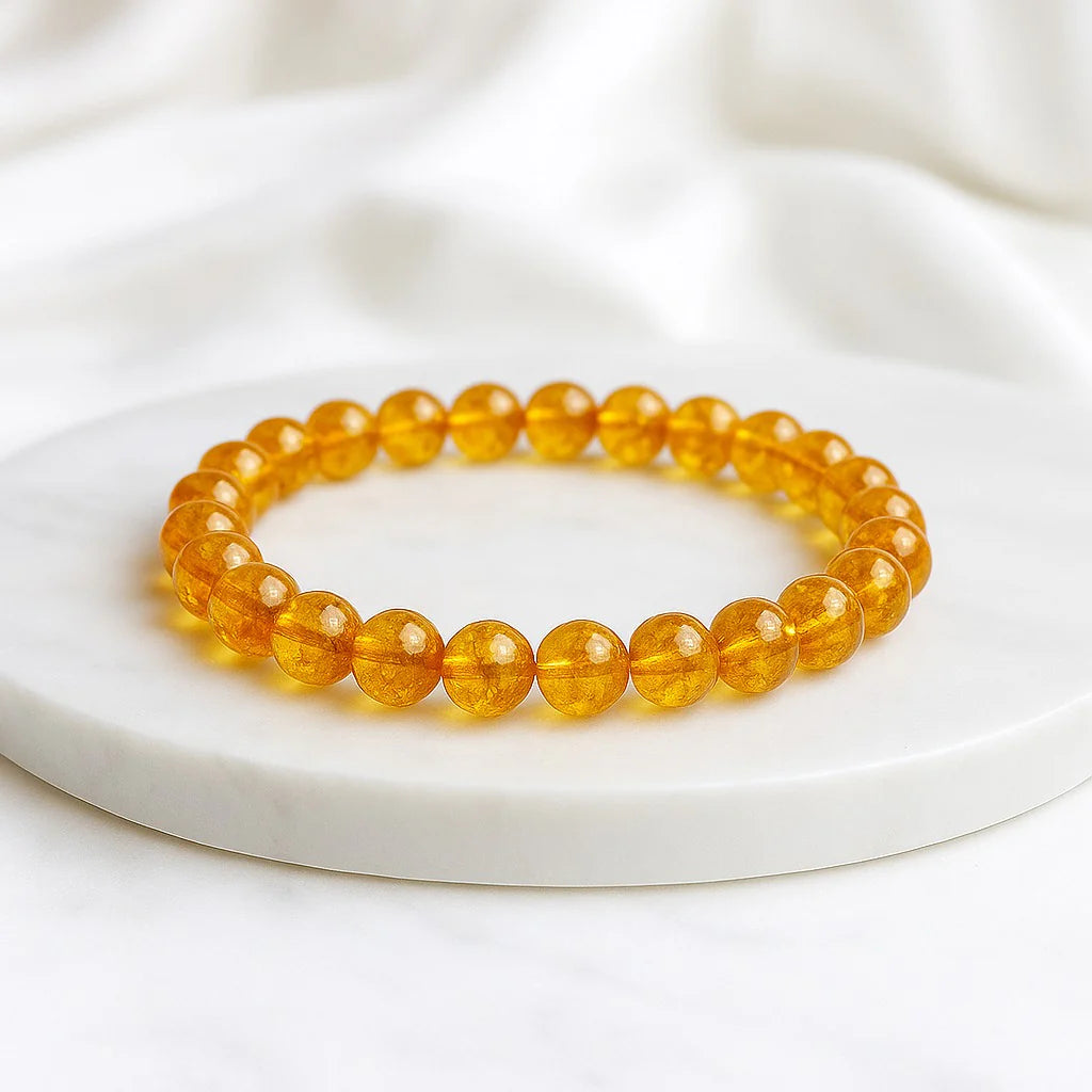 Yellow beaded bracelet on a white plate with a white fabric background