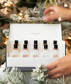 Set of perfume bottles in a gift box with a Christmas tree in the background