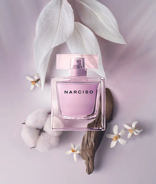 Pink Narciso perfume bottle with white flowers and leaves on a light purple background