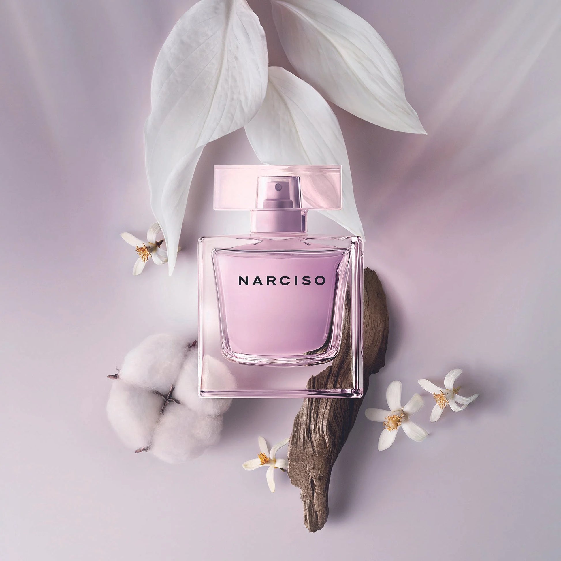 Pink Narciso perfume bottle with white flowers and leaves on a light purple background