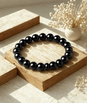 Black beaded bracelet on a wooden surface with decorative elements
