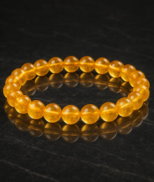Yellow beaded bracelet on a dark reflective surface