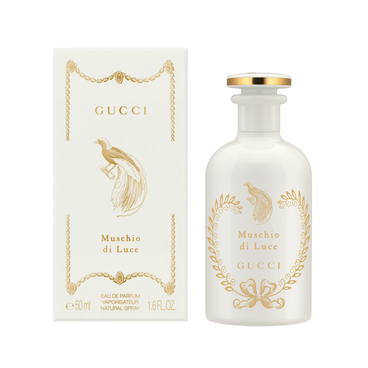Gucci Muschio di Luce Eau de Parfum shown with its white box and frosted glass bottle, both decorated with gold foil detailing and a peacock illustration.