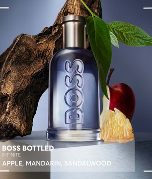 BOSS bottled perfume with an apple and sandalwood on a dark background