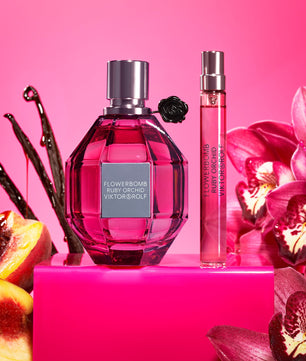 Viktor & Rolf Flowerbomb Ruby Orchid perfume bottles on a pink background with flowers and fruit.
