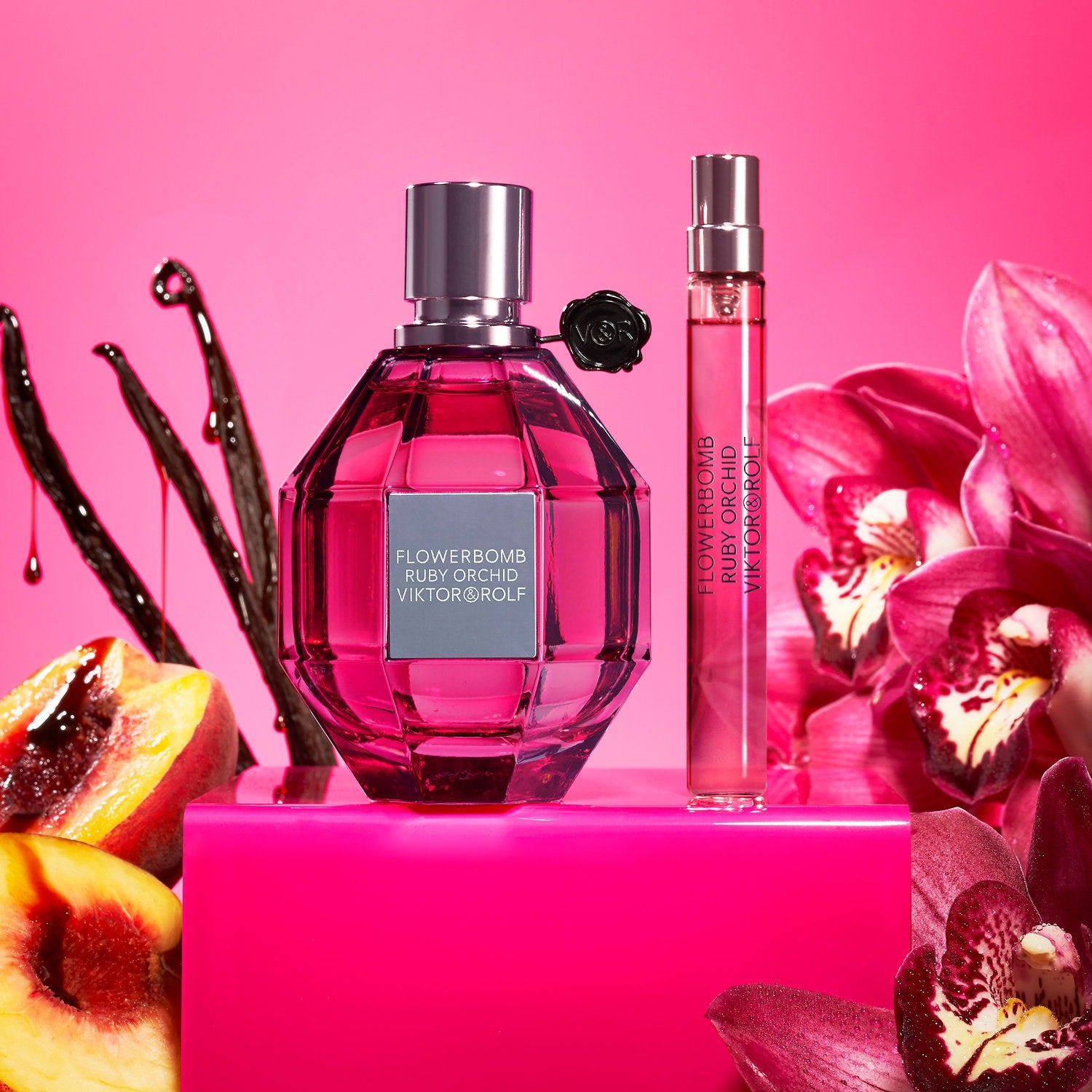 Viktor & Rolf Flowerbomb Ruby Orchid perfume bottles on a pink background with flowers and fruit.