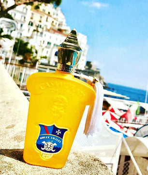 Yellow bottle with a gold cap on a sandy surface with a scenic background