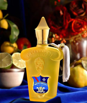 Yellow perfume bottle with gold cap on a blue fabric background