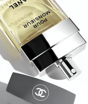 Chanel Monsieur Pour Homme perfume bottle on a reflective surface with a white background