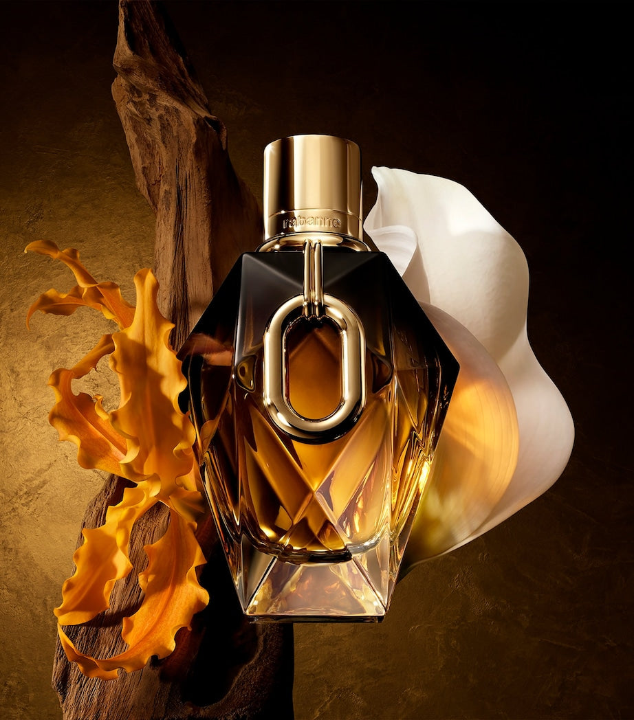 Perfume bottle with gold cap and clear body on a textured brown background